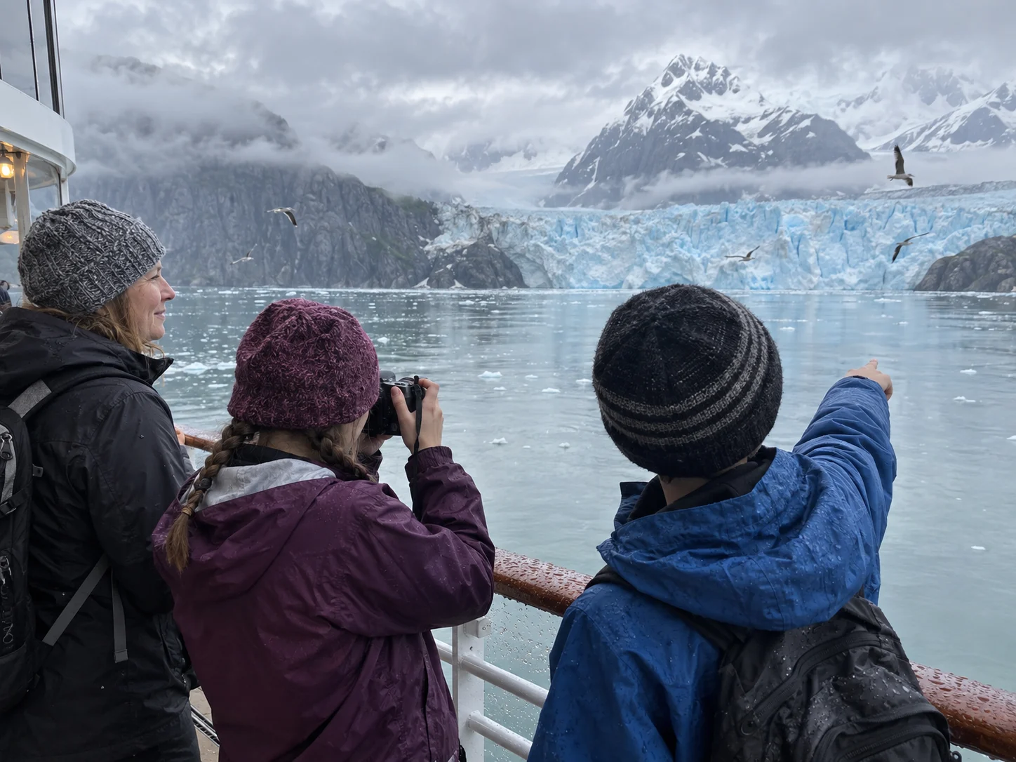 Teenagers watch a glacier and seabirds during an Alaska cruise.