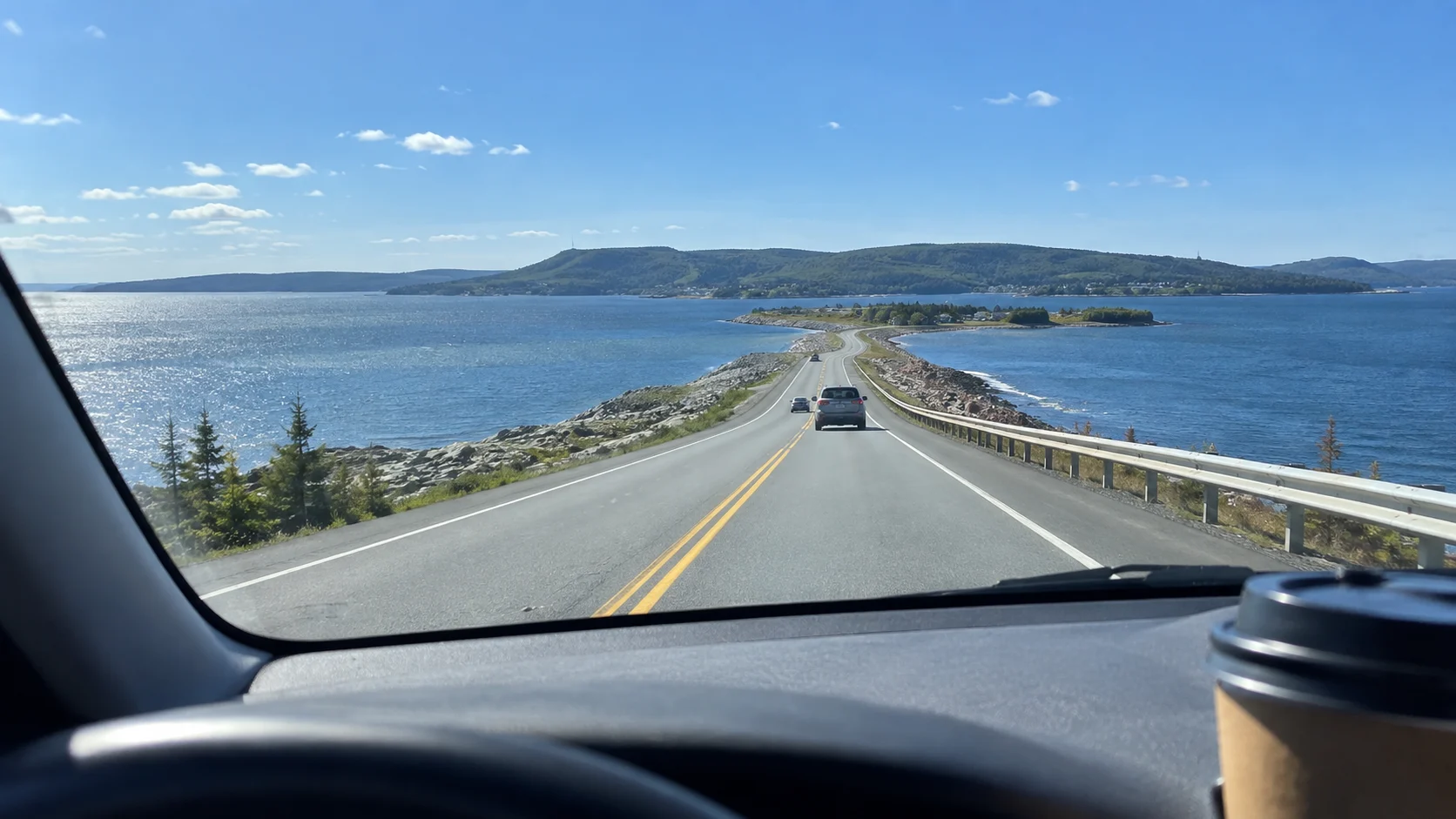 Road crossing blue water toward the hills of Cape Breton Island