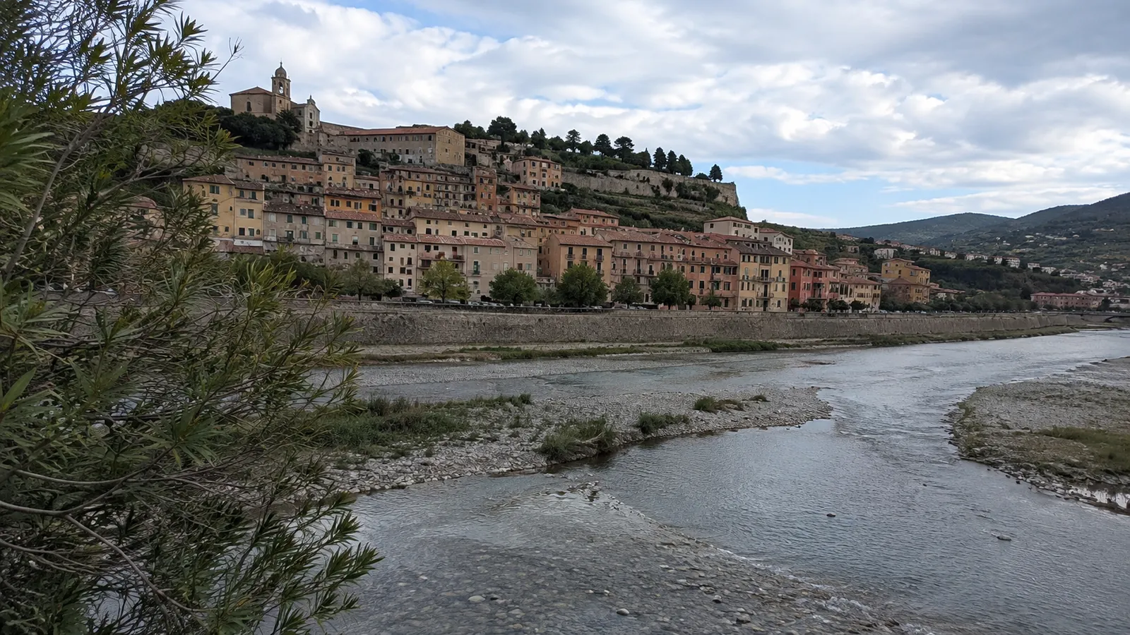 Hillside town overlooks a shallow river and exposed gravel banks.
