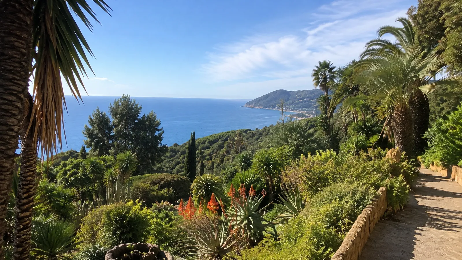 Lush coastal garden with palms and flowering plants above blue sea.