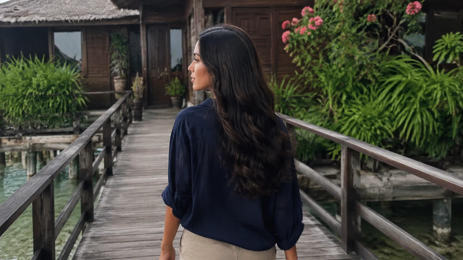 Woman walking along a wooden bridge toward a waterfront chalet.