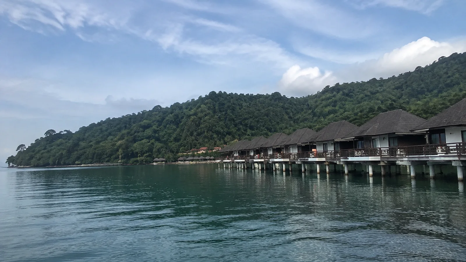Row of waterfront chalets along a green hillside.