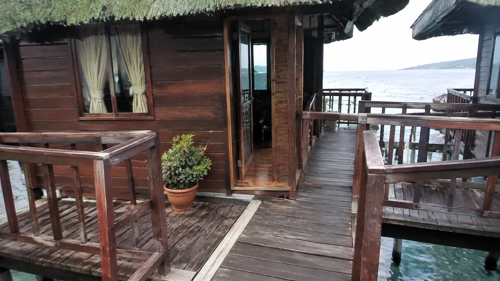 Wooden walkway leading to the doorway of an overwater cottage.