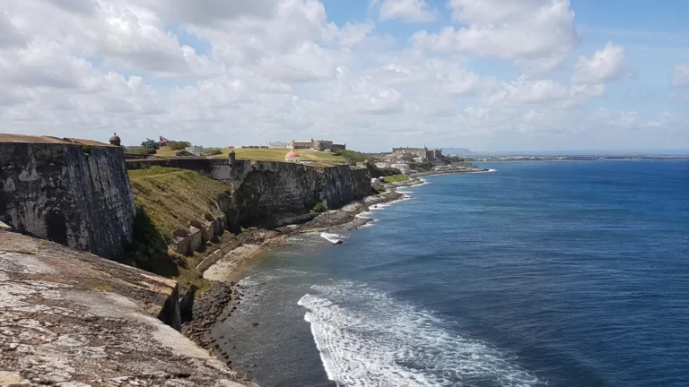 Old stone coastal fortifications overlooking waves and blue ocean.