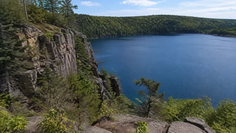 Blue lake surrounded by forest and steep rocky cliffs.