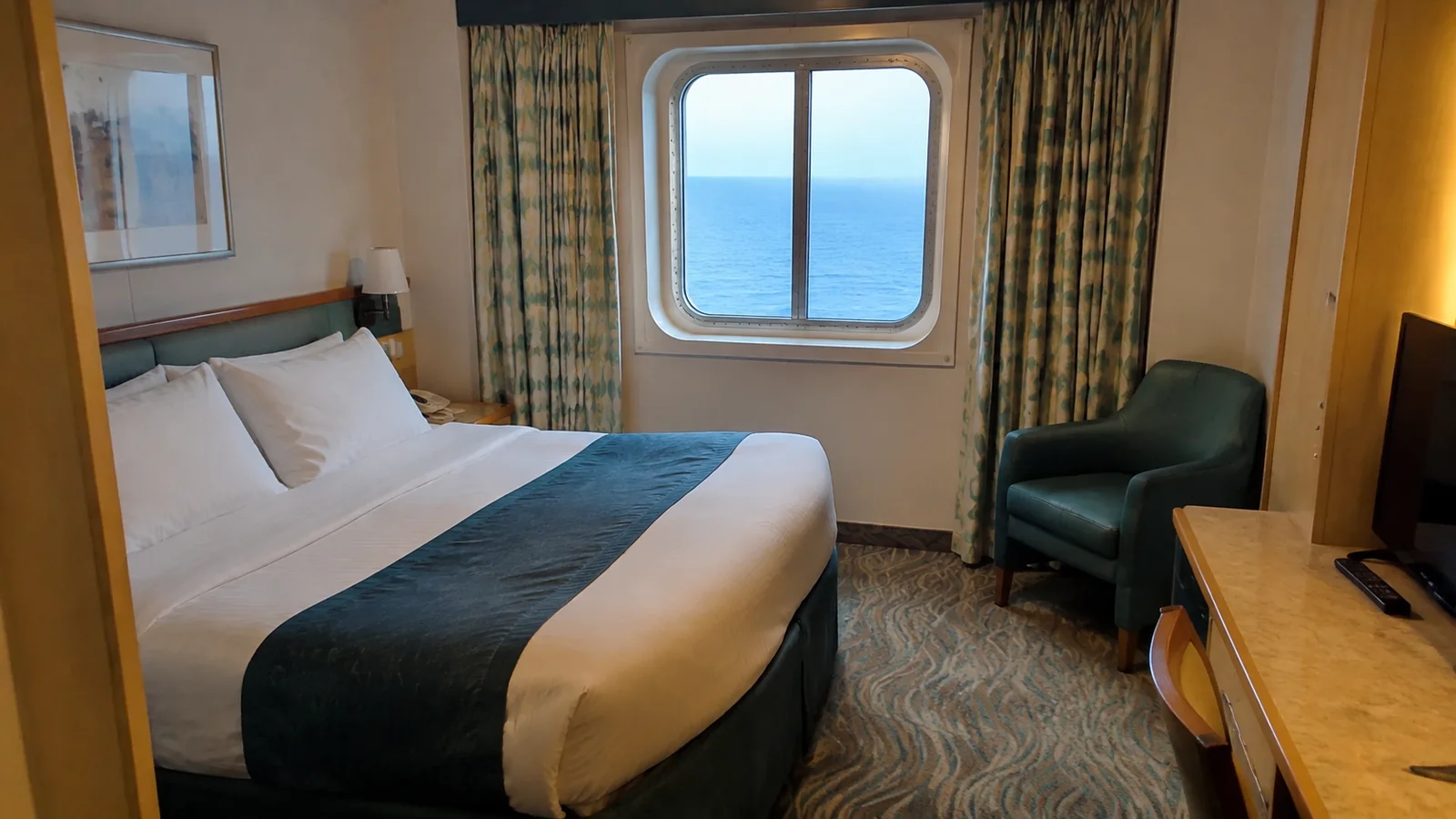 Double bed and armchair in a cabin with a sea-view window.