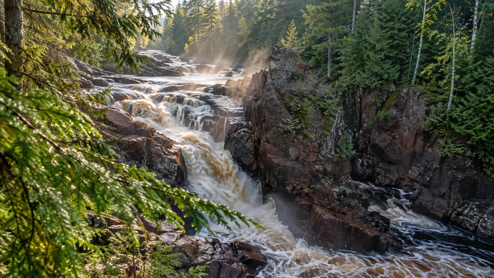 Brownstone Falls rushing down rugged red-brown rock through hemlock forest at Copper Falls State Park.