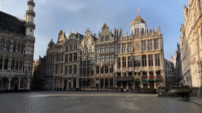 Ornate historic buildings line a broad cobbled city square.