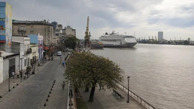 Cruise ship docked along a wide river beside a city waterfront