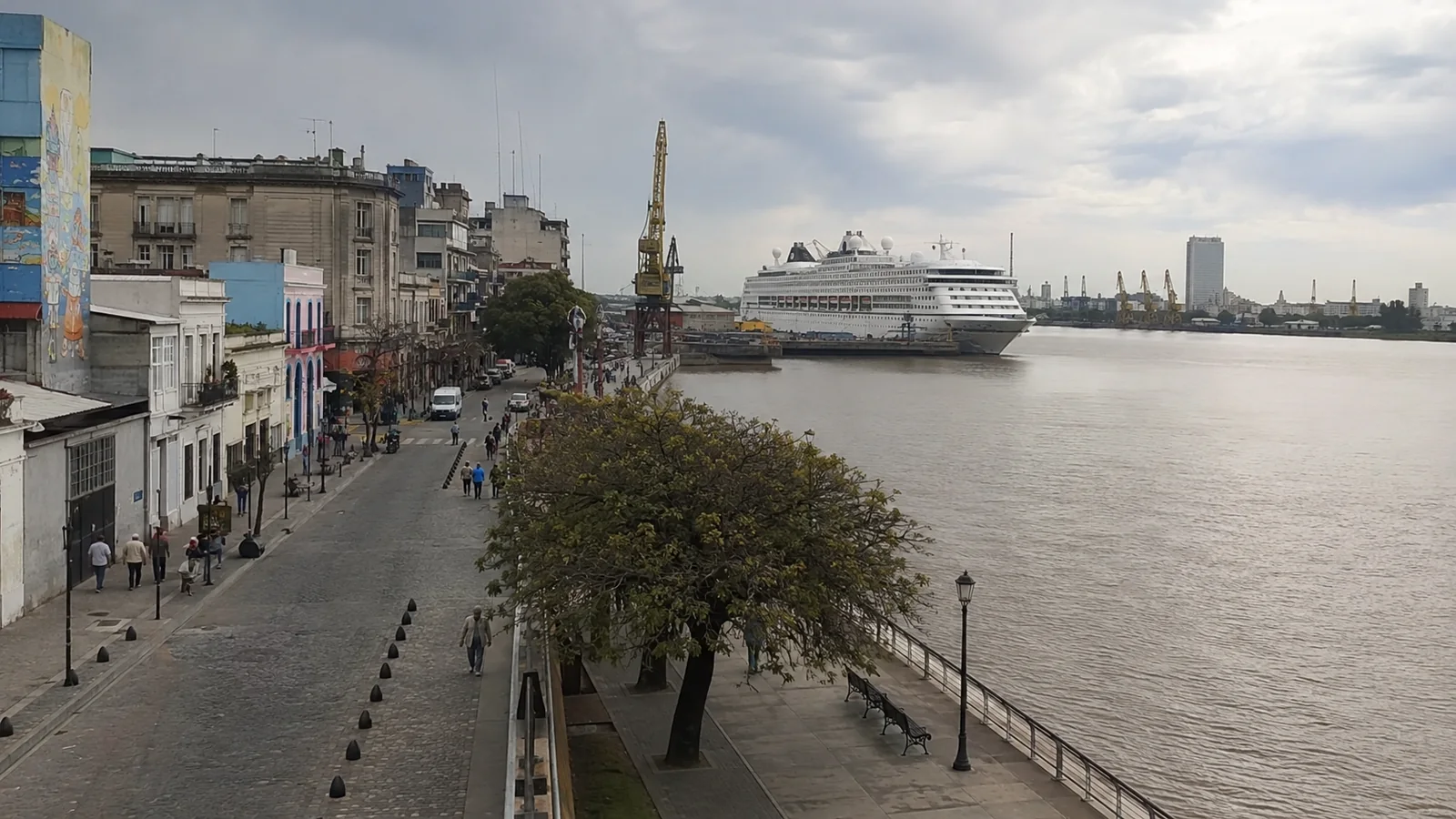 Cruise ship docked along a wide river beside a city waterfront