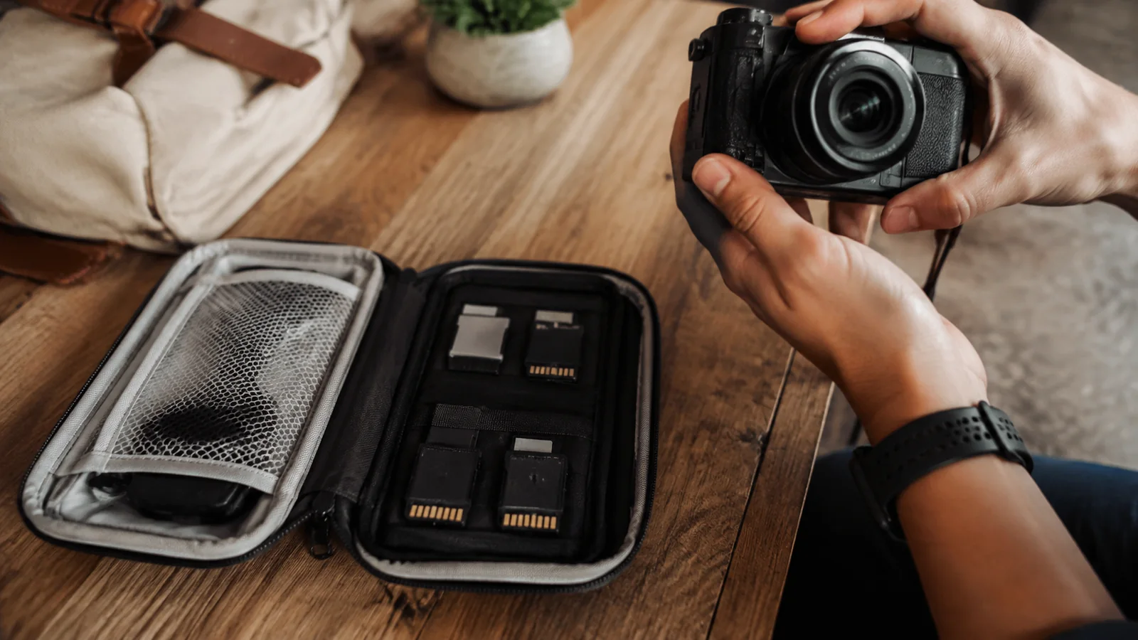 Hands holding a camera beside an open case of memory cards.