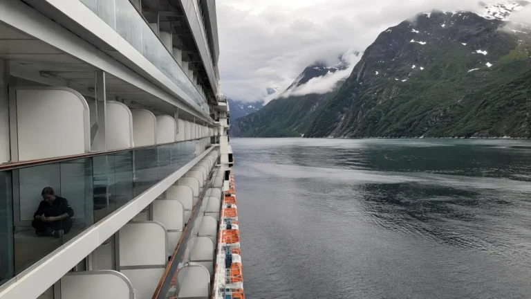 Exterior view along a cruise ship's stacked balcony cabins in a fjord