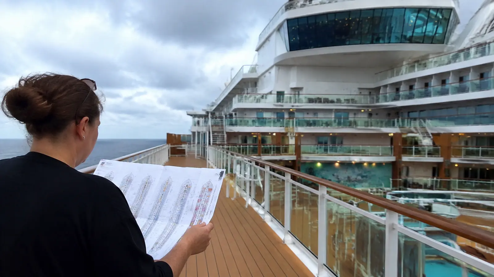 Woman standing on a cruise ship deck reading a printed deck plan