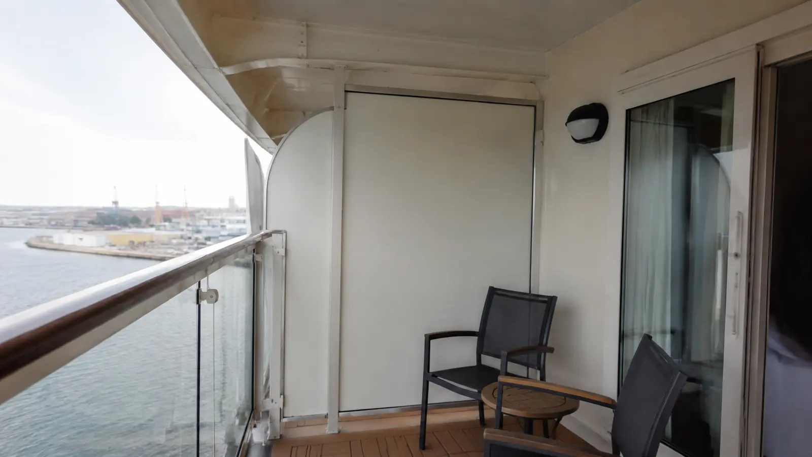 Empty cruise ship balcony with two chairs and a small table