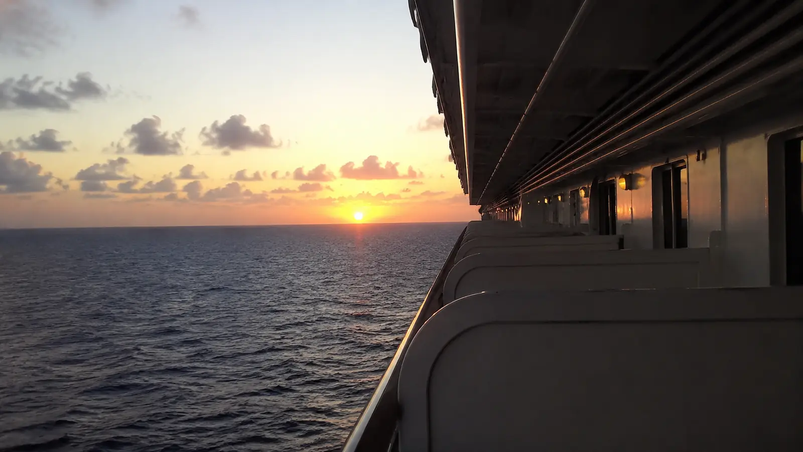 Rows of cruise ship balconies overlooking the ocean at sunset