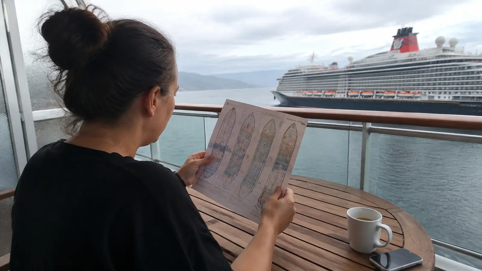 Woman reviewing a printed cruise ship deck plan at a balcony table