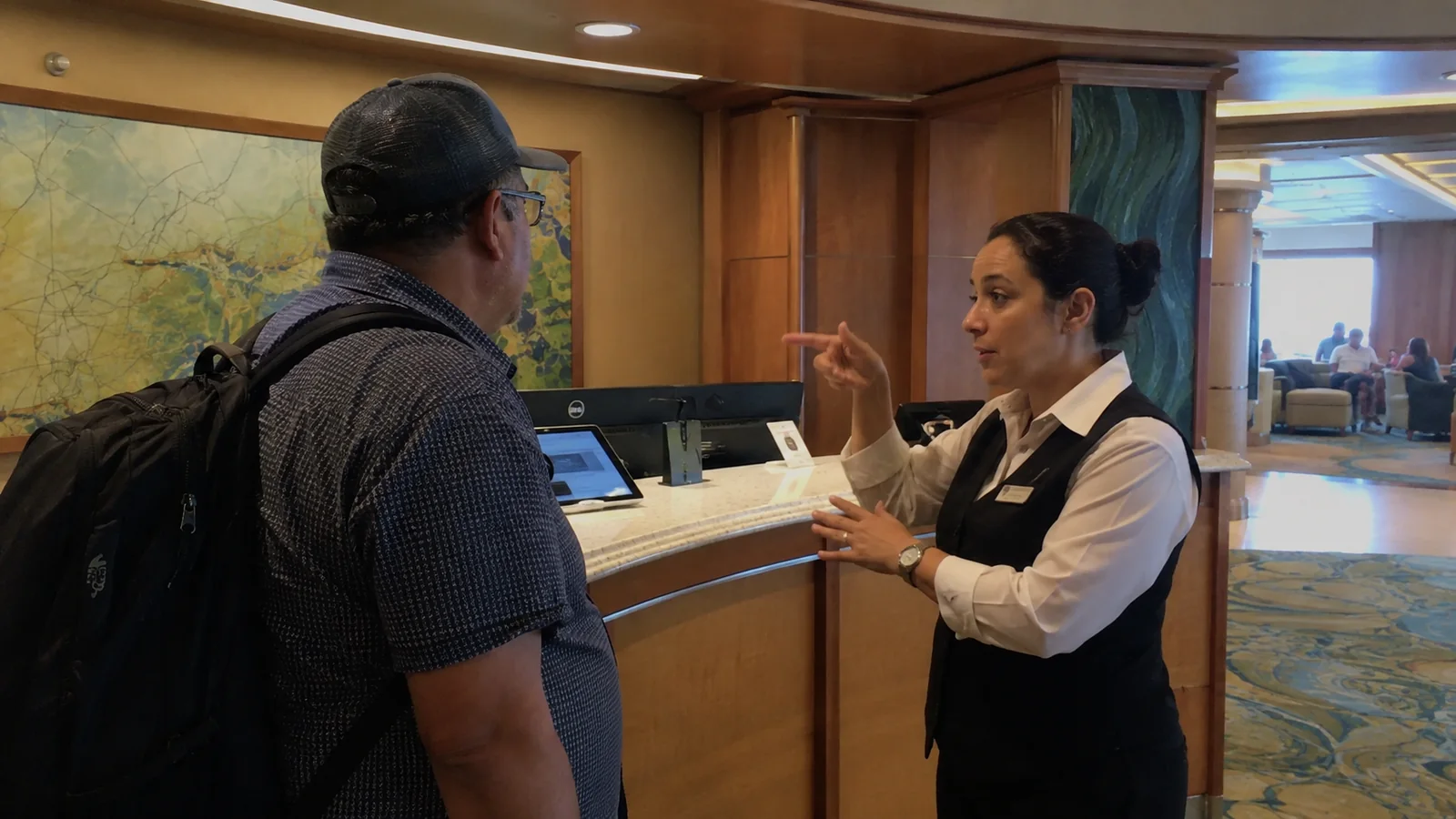 Passenger speaking with a crew member at the ship's reception desk.