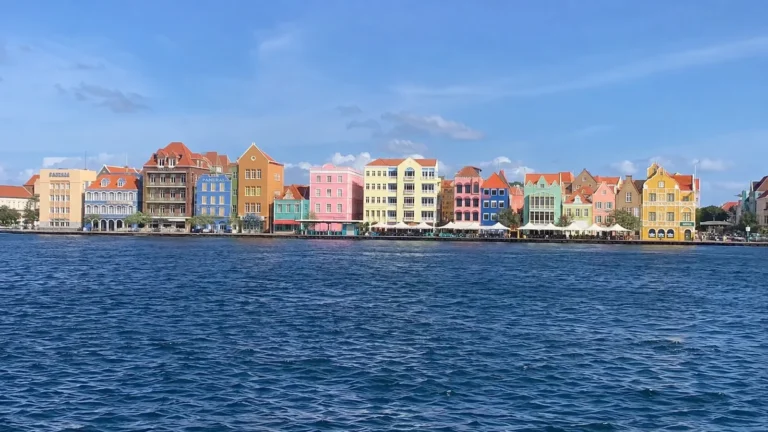 Row of colorful gabled waterfront buildings across deep blue water.