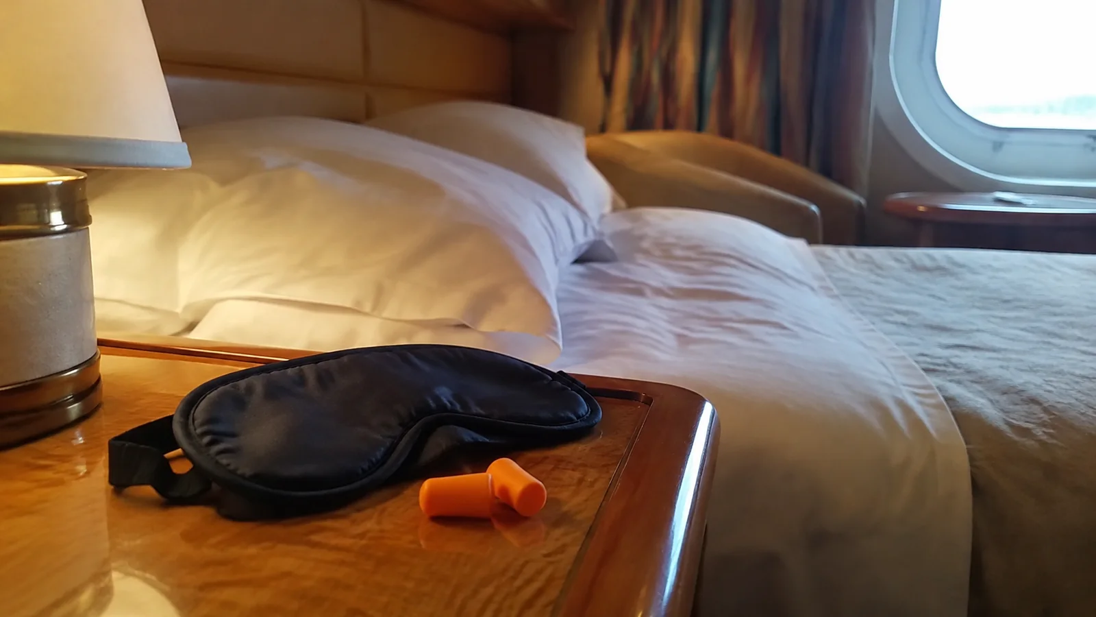 Sleep mask and orange earplugs lie on a bedside table.