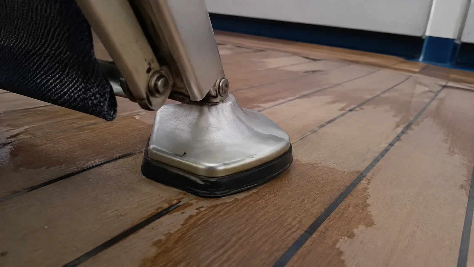 Close view of a metal furniture support fixed to a wooden deck.