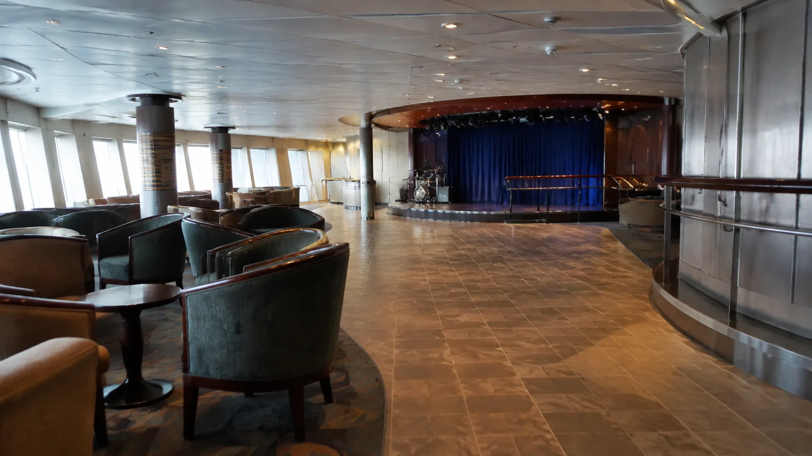 Empty ship lounge with a dance floor and curtained stage.