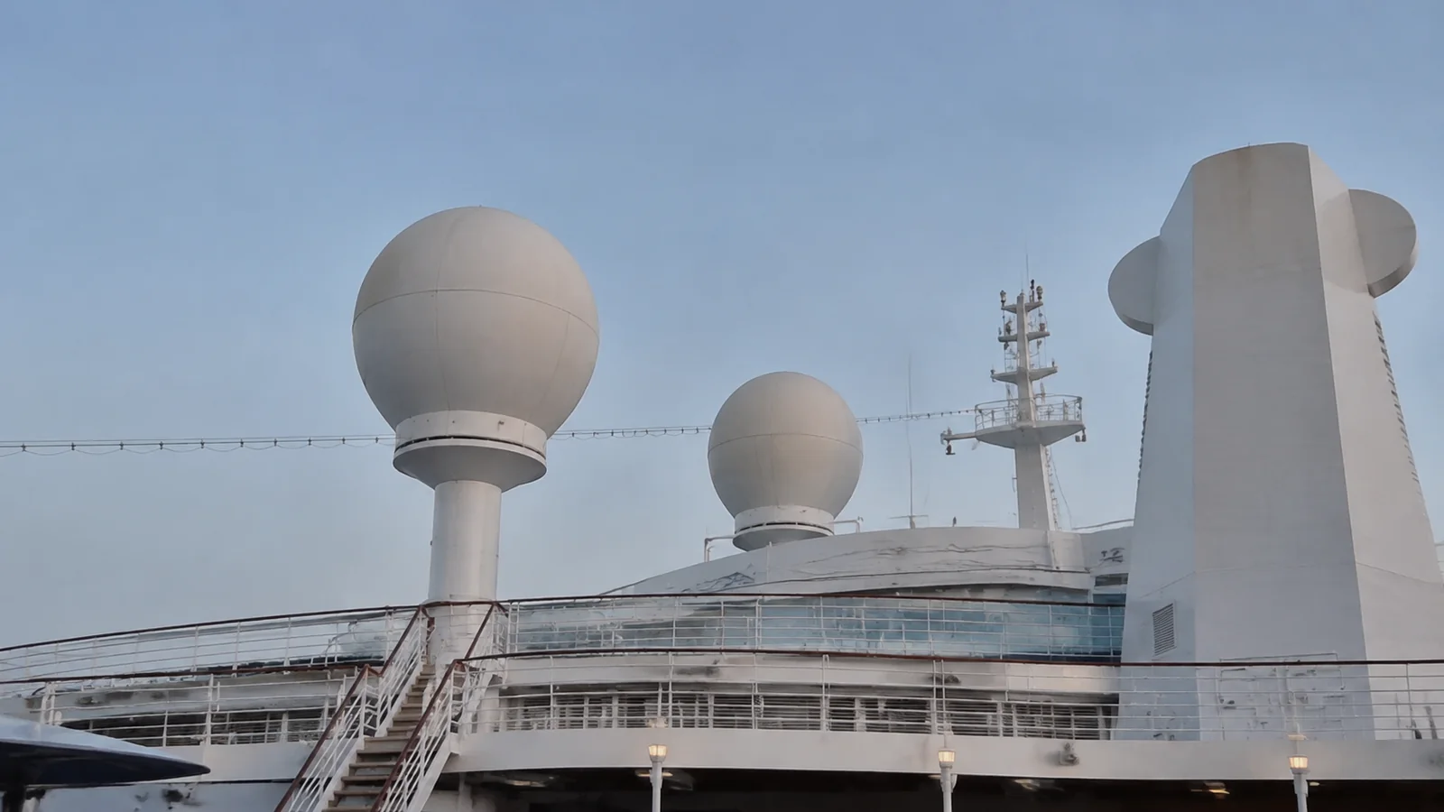 White satellite domes and antenna equipment on a ship's upper deck.