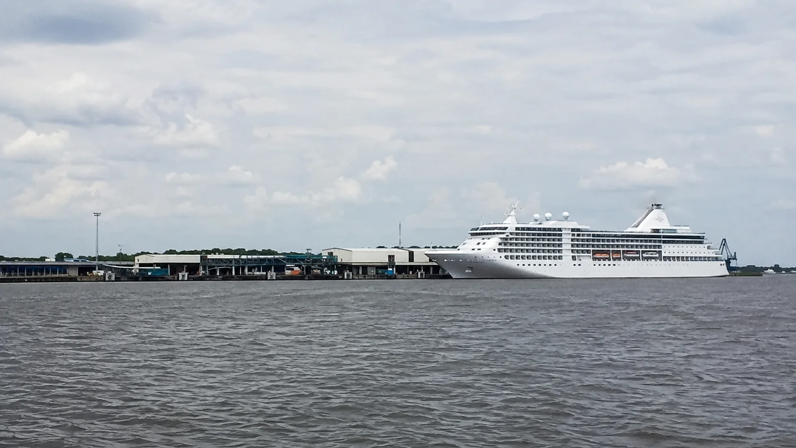 White cruise ship docked across a harbor