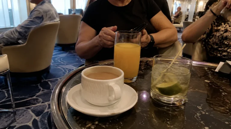 Coffee, orange juice and a lime drink on a ship lounge table.