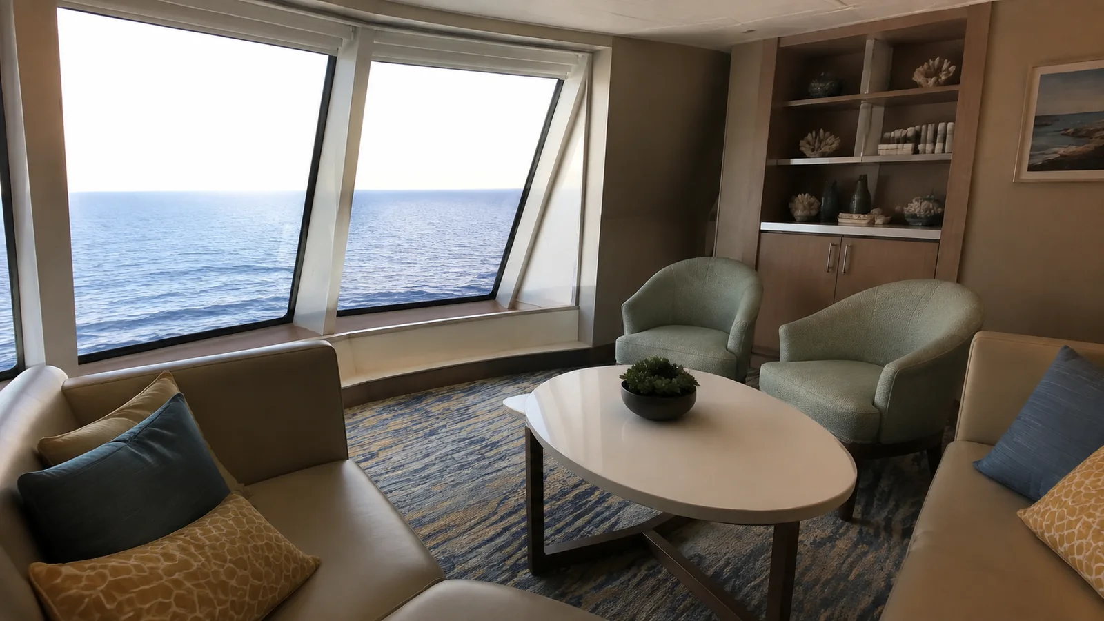 Empty lounge has armchairs and a round table beside ocean windows.