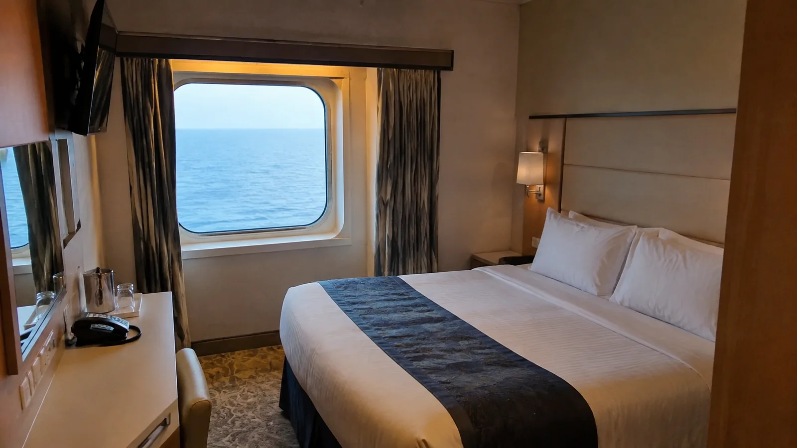 Compact stateroom contains a double bed and ocean window.