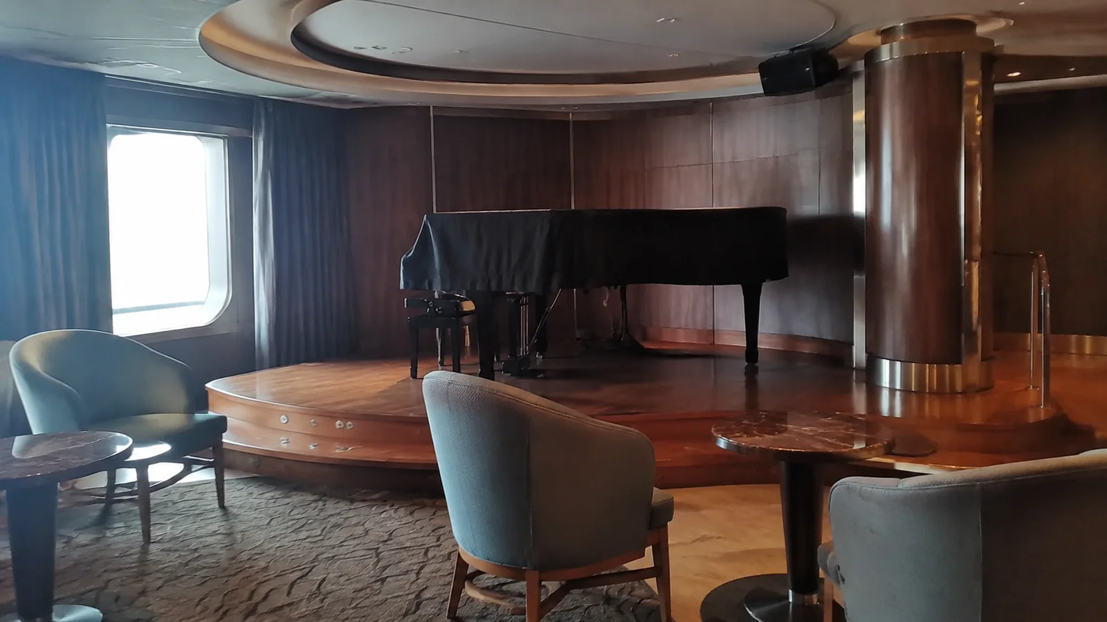 Covered grand piano stands on a small lounge stage.