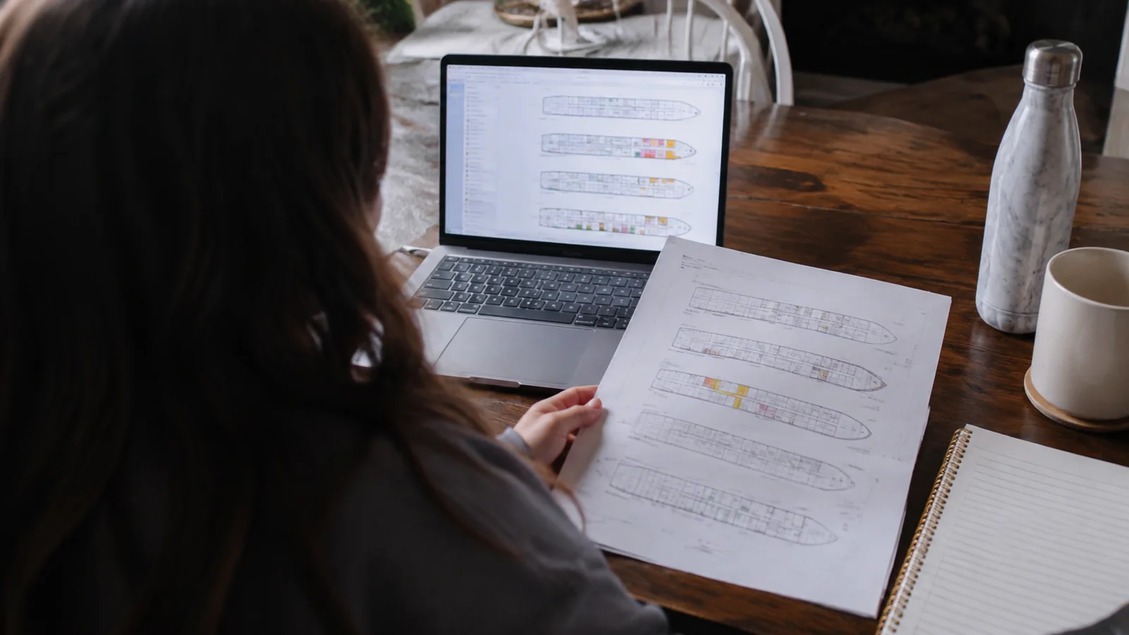 Woman comparing a printed cruise ship deck plan with a laptop