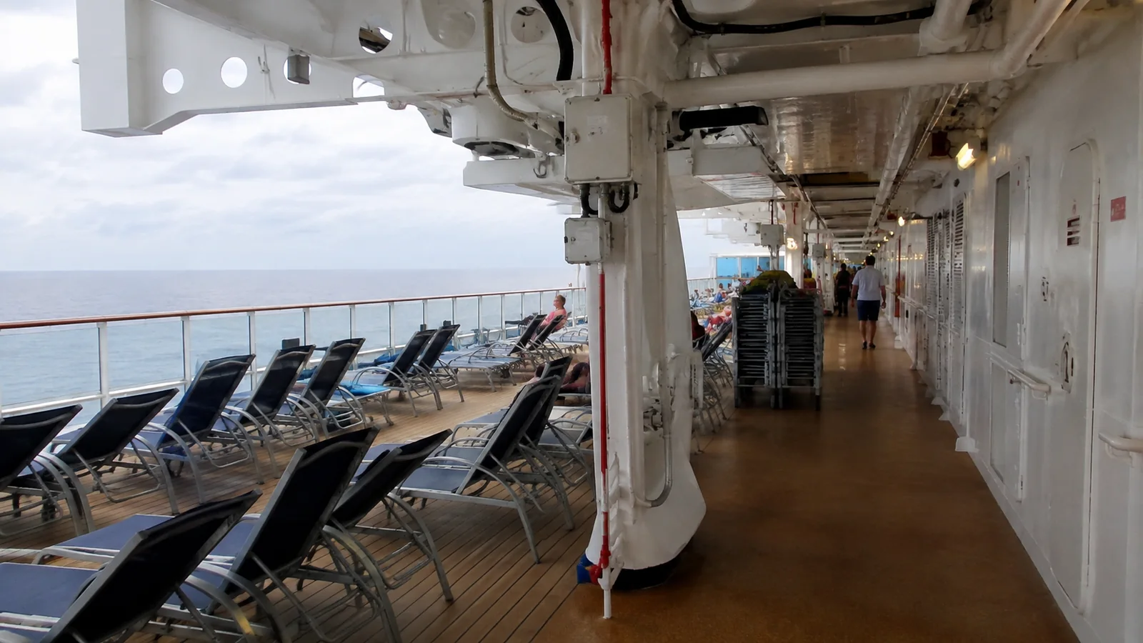 Lounge chairs along a covered cruise ship promenade
