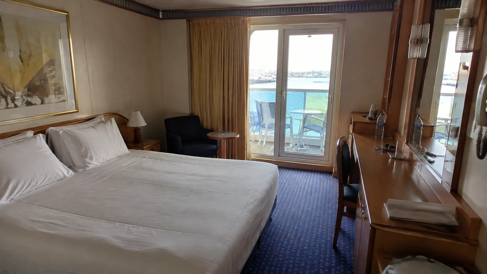 Cruise cabin with a double bed and balcony doors at the far end.