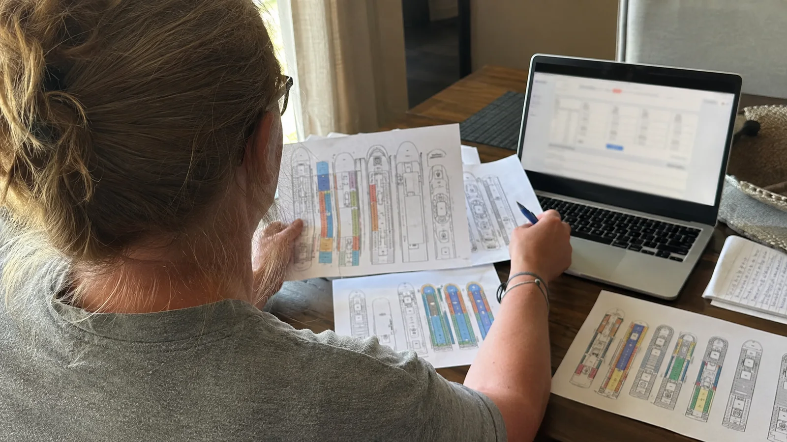 Woman comparing printed cruise ship deck plans with a laptop