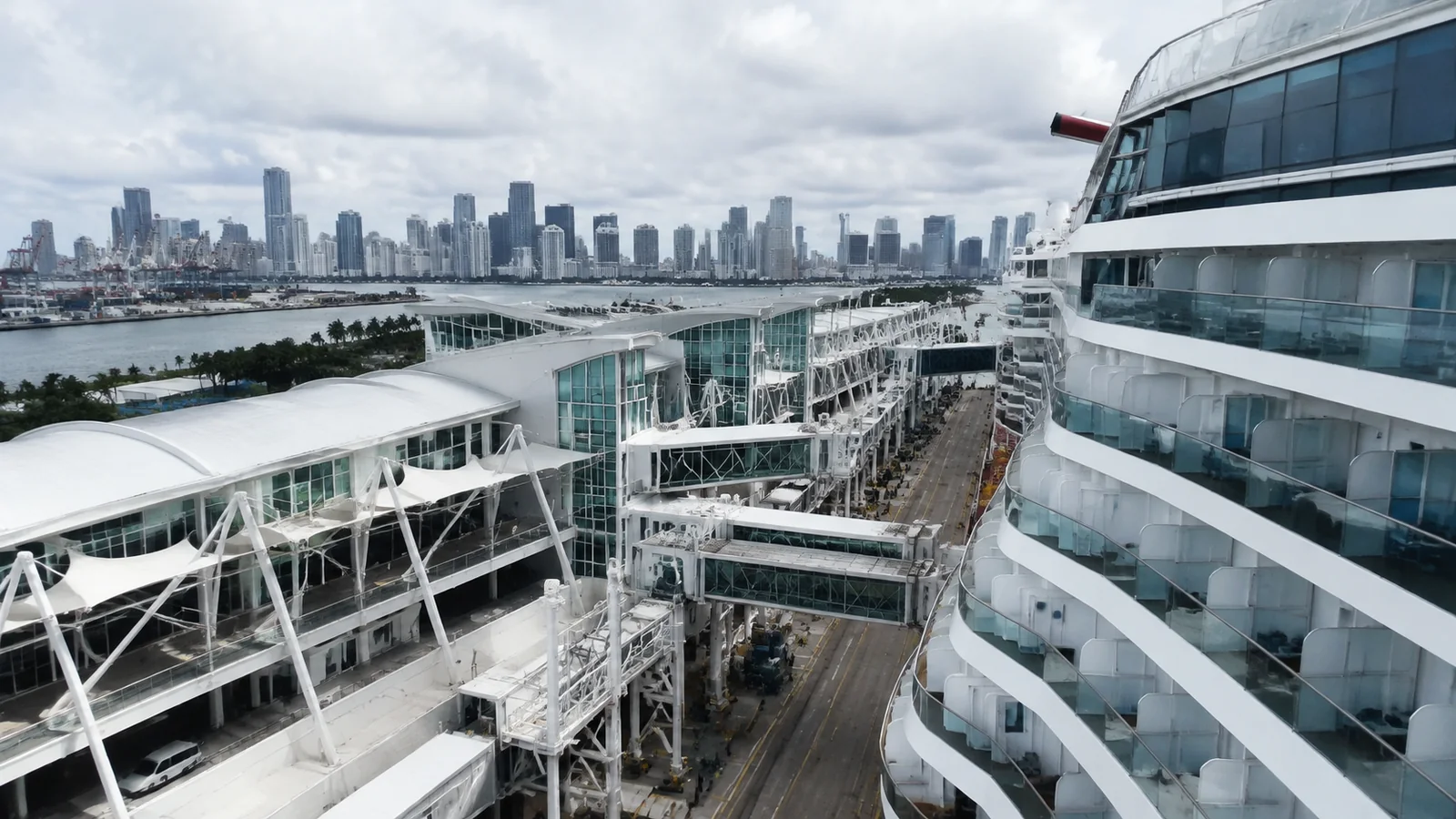 Cruise terminal gangways and a docked ship with a city skyline behind