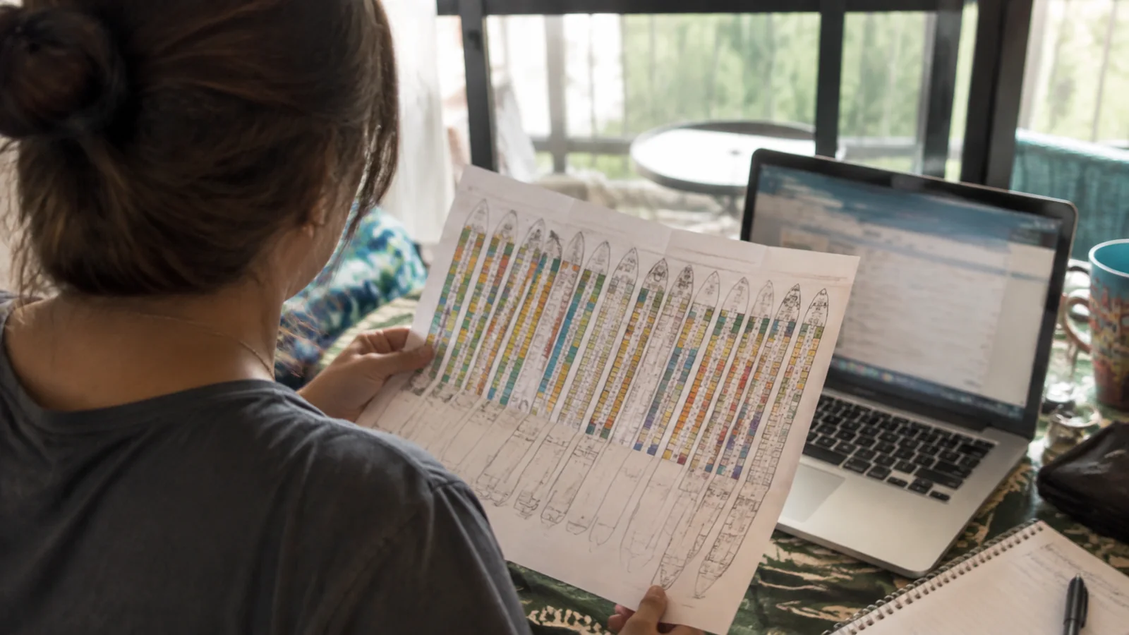 Woman reviewing a printed cruise ship deck plan beside a laptop