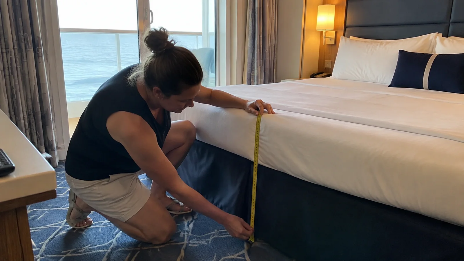 Woman uses a tape measure to measure the height of a cabin bed.