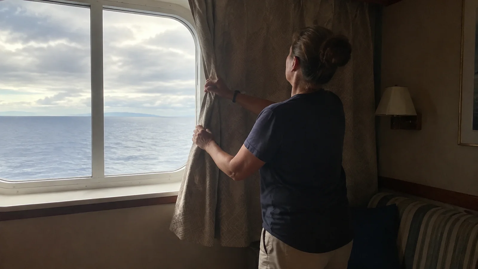 Passenger tying back curtains beside a cabin window.