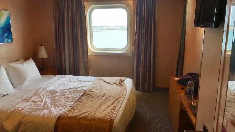 Cruise cabin with a double bed and an ocean-view window