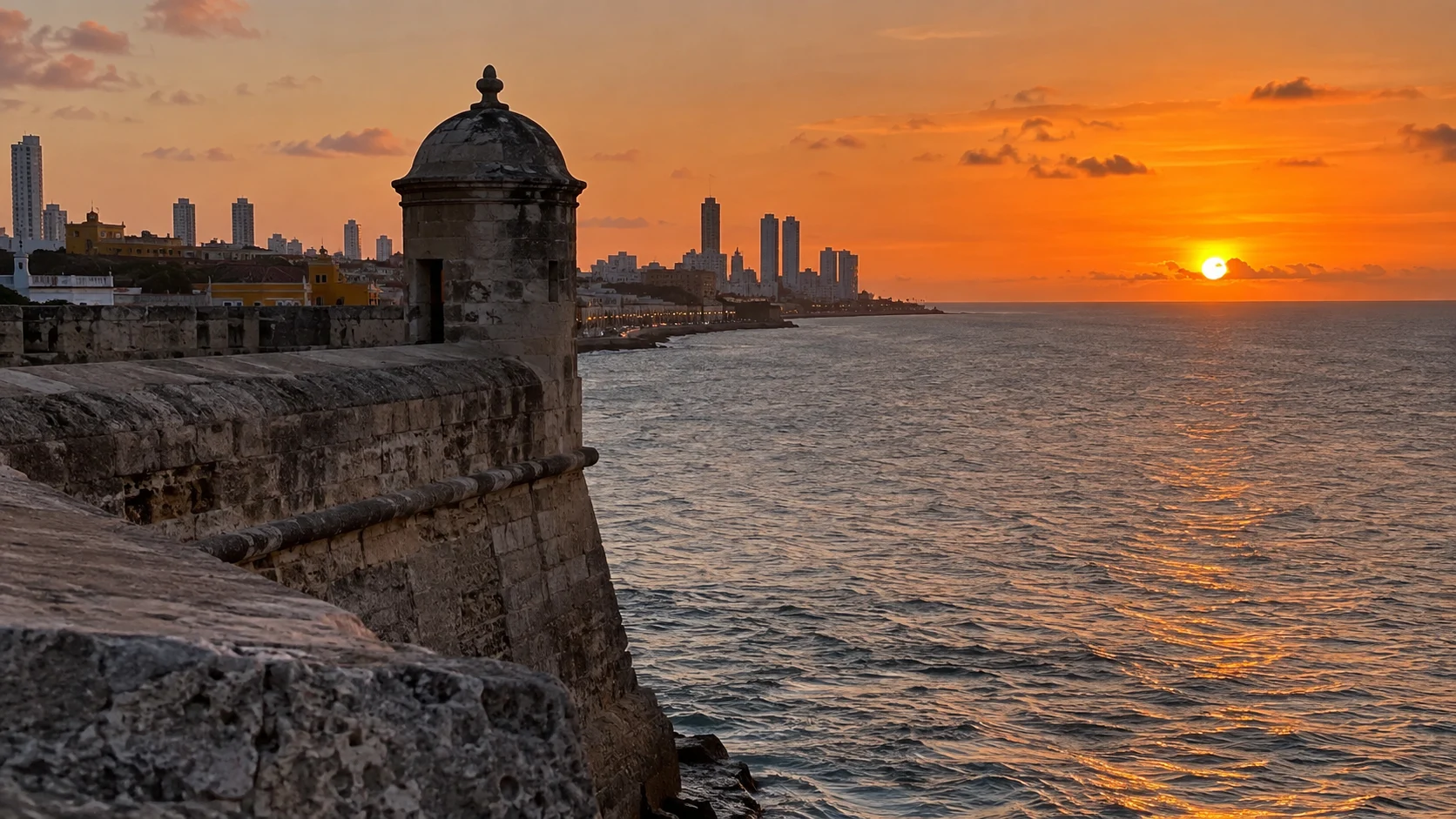 Historic Cartagena ramparts overlooking the Caribbean Sea at sunset.