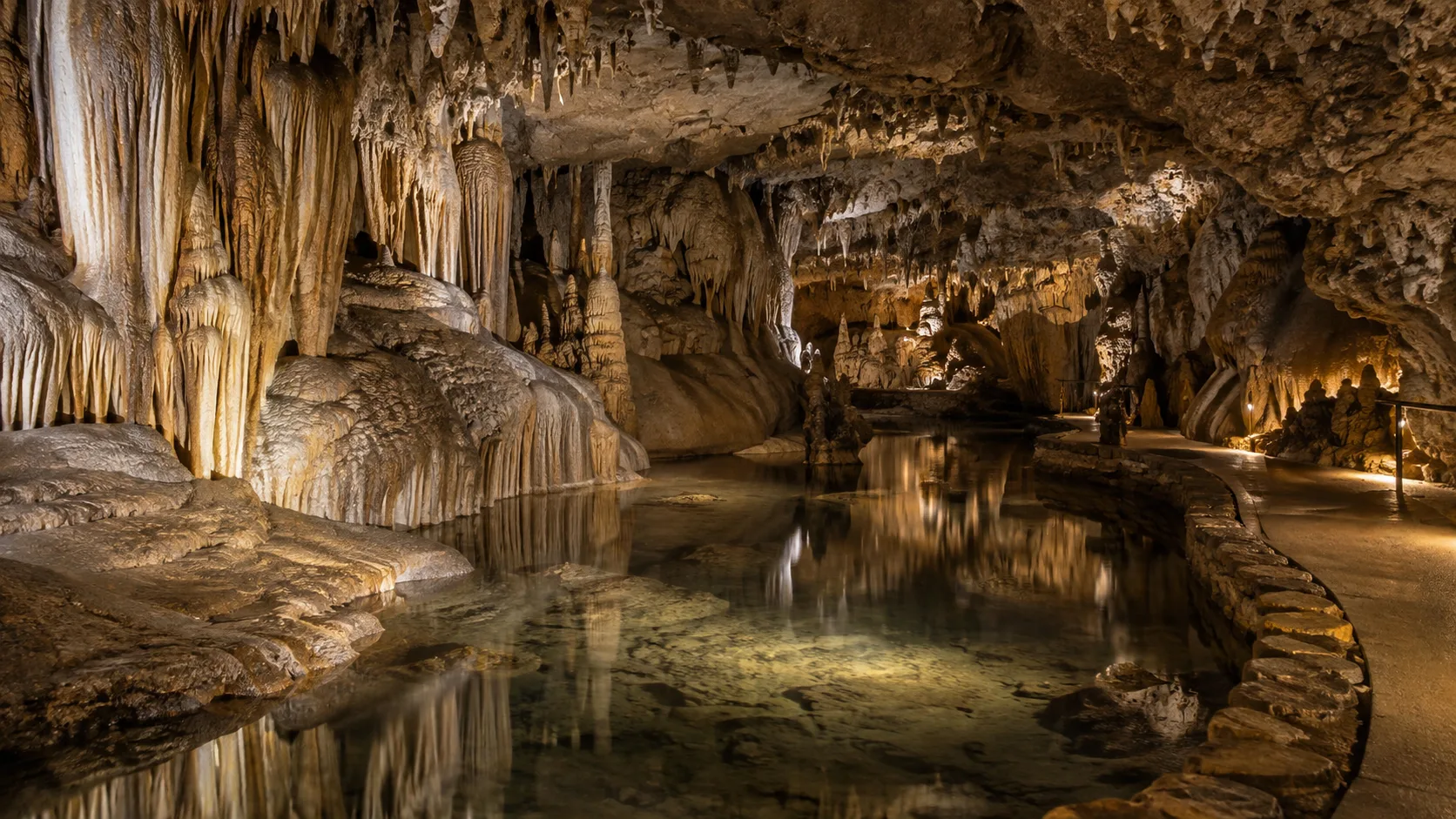 Flowstone formations and stalactites surround a reflective pool inside Cave of the Mounds.