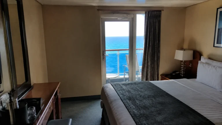 Double bed faces a narrow balcony door with an ocean view.