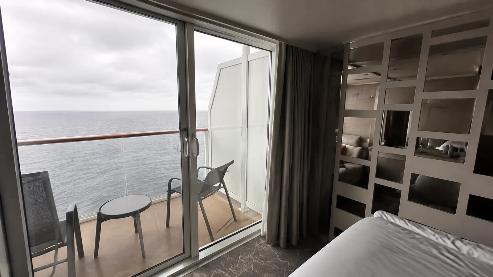 Balcony doors beside a bed and mirrored cabin partition.