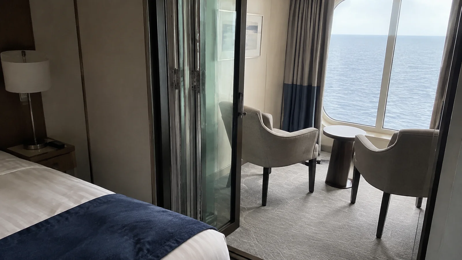 Glass folding doors separate a bed from window-side chairs.