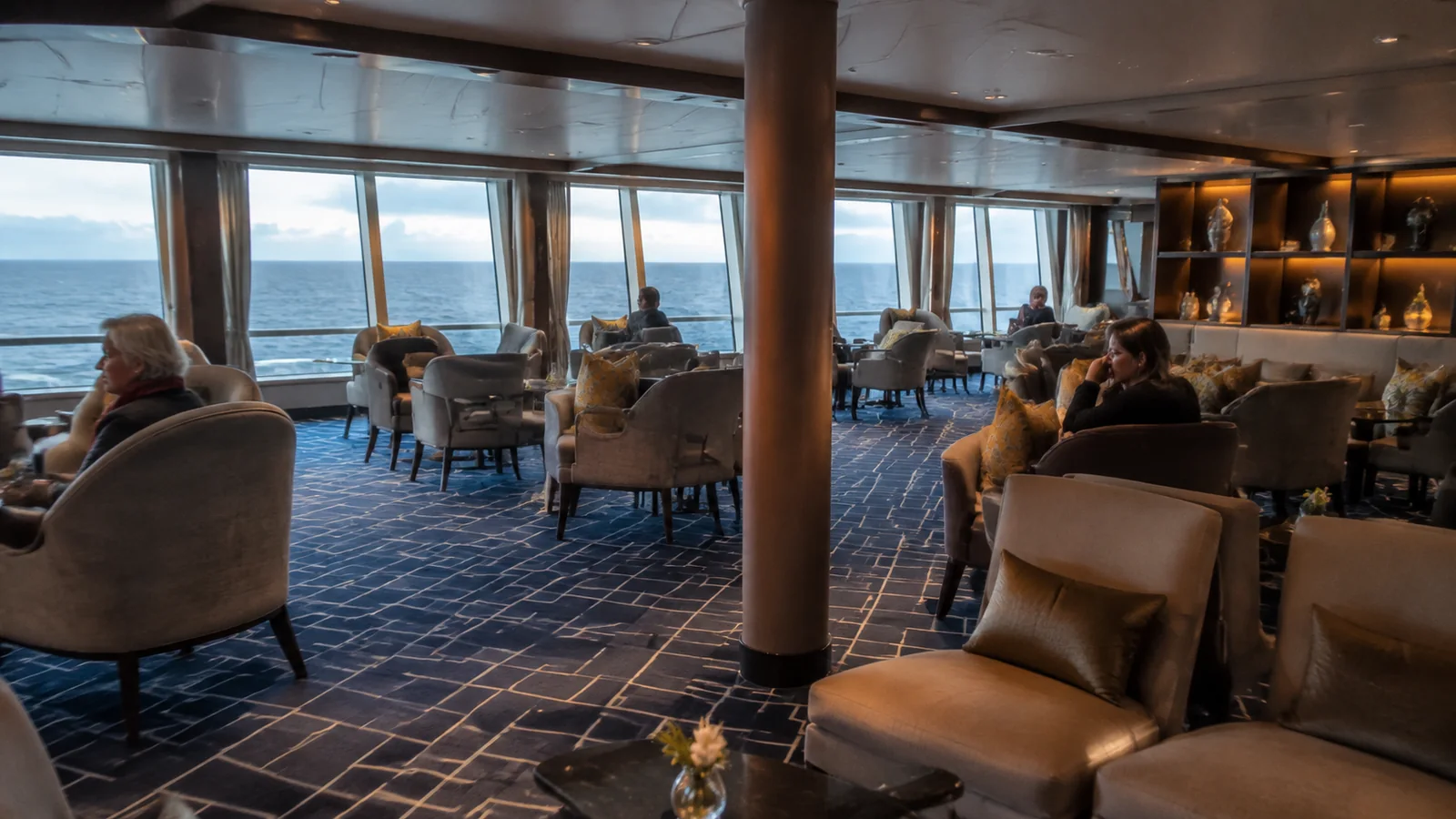Passengers relax in a spacious lounge overlooking the ocean.