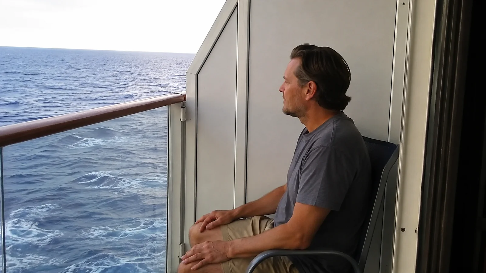 Passenger seated on a small balcony facing the ocean.