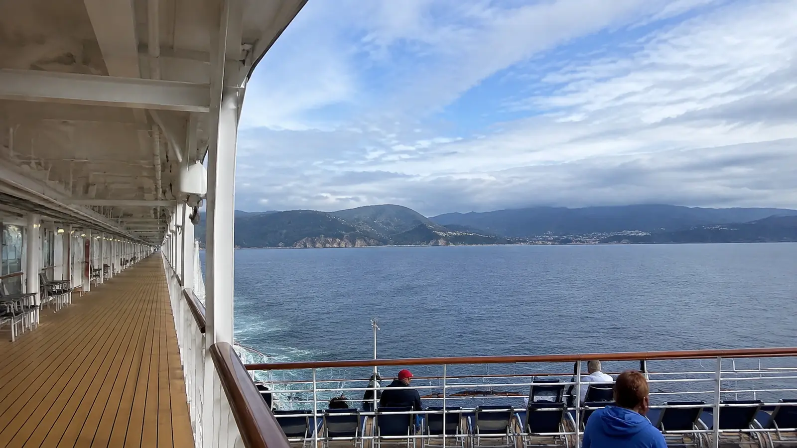 Open cruise ship promenade overlooking the sea and distant mountains