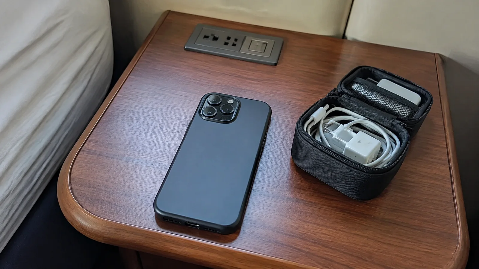 Phone and an open cable organizer rest on a wooden desk.