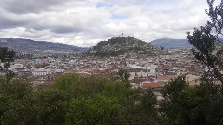 Wide view across a densely built city surrounded by green hills.
